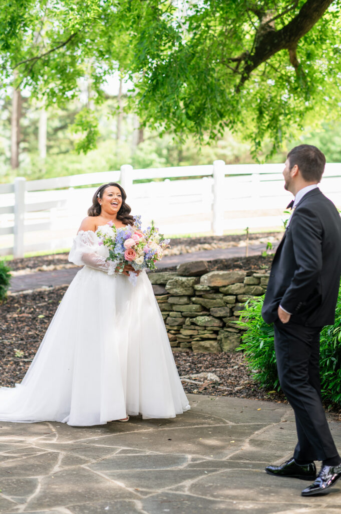 bride laughs seeing groom during first look at Historic Wakefield Barn near Raleigh, NC